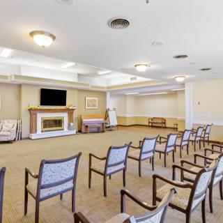 An empty conference room with chairs arranged in rows, featuring a television and a fireplace.