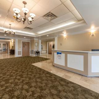 A spacious lobby area with chandeliers, a carpeted floor, and a reception desk.