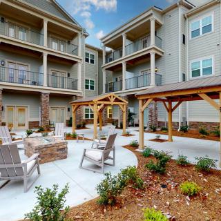A modern apartment complex featuring an outdoor seating area with pergolas and well-maintained landscaping.