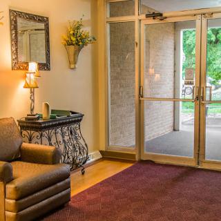 A cozy lobby area featuring comfortable seating, a stylish lamp, and an inviting entrance.