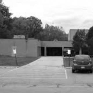 A parking lot in front of a building, surrounded by trees.