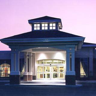 An illuminated building entrance at twilight with a prominent portico.