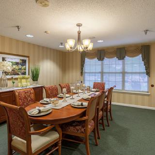 A beautifully set dining room with an elegant table and chairs, illuminated by a chandelier.