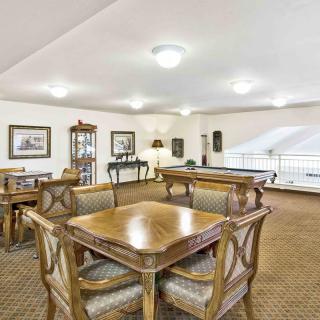 A spacious and elegantly furnished dining area with wooden tables and chairs, set under soft ceiling lights.