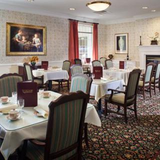 An elegantly decorated dining room with neatly arranged tables and chairs, featuring sophisticated interior design and a carpeted floor.