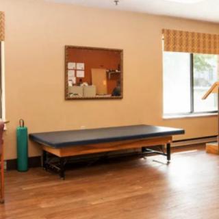 A minimalistic therapy room with an exercise mat and large window.