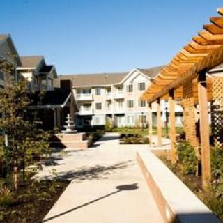 A residential complex with a landscaped garden and a pathway under a pergola.