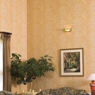 A cozy living room corner featuring a framed painting, potted plant, and elegant curtains.