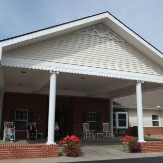 A building entrance with a porch featuring columns and brickwork.
