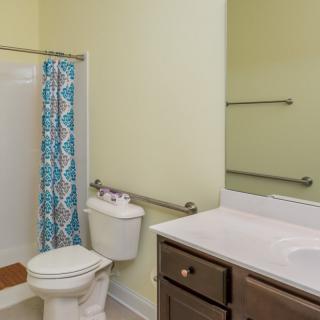 A small bathroom with a toilet, sink, and shower area featuring a colorful shower curtain.