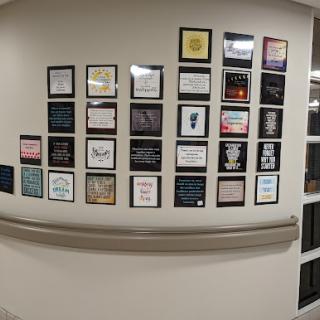 A collection of framed inspirational quotes displayed on a wall in a hospital corridor.