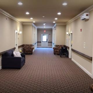 A well-lit hallway with sofas and carpeted flooring.