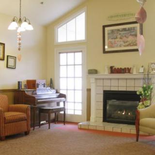A cozy living room featuring a fireplace, piano, and comfortable seating.