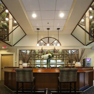 A modern hotel lobby with a reception desk, elegant lighting, and decorative mirrors.