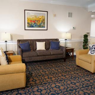 A cozy living room setup featuring a sofa and armchairs, complemented by a decorative painting and soft lighting.