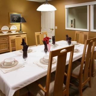 A warmly lit dining room featuring a neatly set table with wooden chairs and decorative elements.