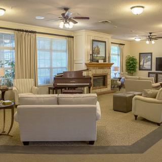 A cozy living room featuring a piano and fireplace, with comfortable sofas and elegant decor.