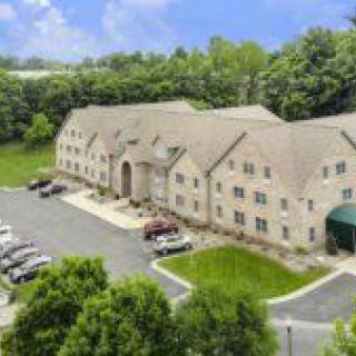 Aerial view of a building with a parking lot surrounded by trees.
