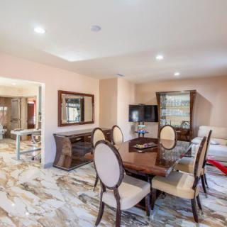 A well-furnished dining room with a wooden table, upholstered chairs, and elegant decor.