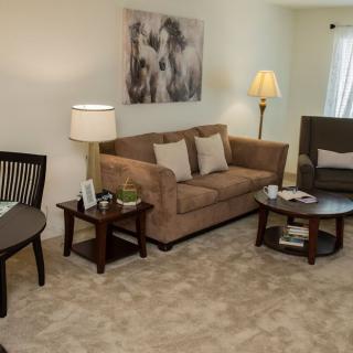 A cozy living room with a sofa, side tables, lamps, and artwork on the wall.