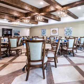 A spacious dining room featuring elegant chairs and tables, with wooden beams and chandeliers enhancing the ambiance.