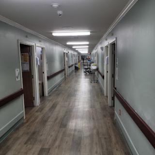 A view of a hospital hallway with several doors and bright overhead lighting.