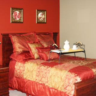 A luxurious bedroom with red and gold bedding, complemented by decorative wall art.