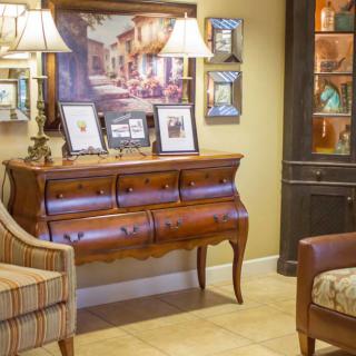 A cozy living room corner featuring a wooden console table adorned with framed photos, table lamps, and decorative artwork.