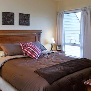 A cozy bedroom with a wooden bed, decorative pillows, and a large window.