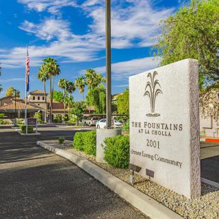 Entrance to a retirement community with palm trees and a clear blue sky.