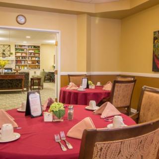 A well-arranged dining area with tables set for service, featuring red tablecloths and neatly folded napkins.