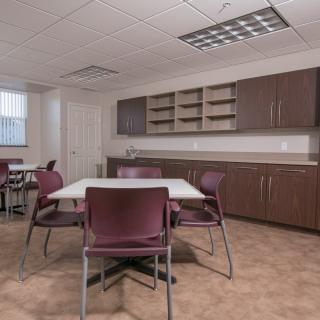 A clean and organized office meeting room with tables, chairs, and cabinets.