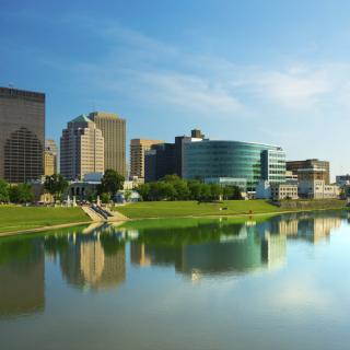 Scenic view of a city skyline with buildings reflecting in a calm river.