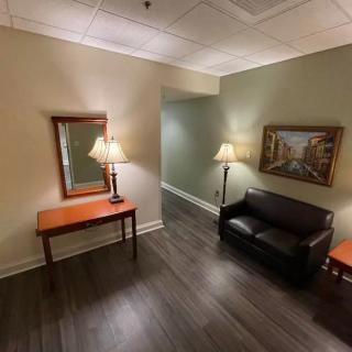 A cozy lobby area with a sofa, table, mirror, and lamps.