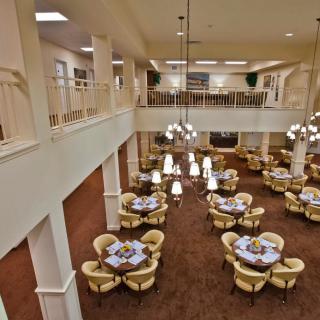 An elegant indoor dining area with multiple tables and chairs, featuring large chandeliers.
