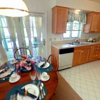 A cozy kitchen with a dining area, featuring wood cabinets and a table set for a meal.