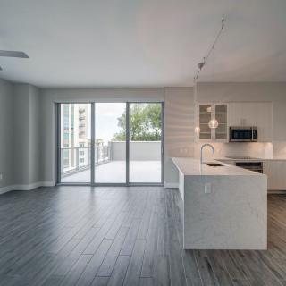 A modern open floor plan apartment featuring a kitchen and living area with access to a balcony.