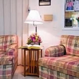 A cozy living room setup featuring plaid armchairs, a small wooden table with a floral arrangement, and a lamp.