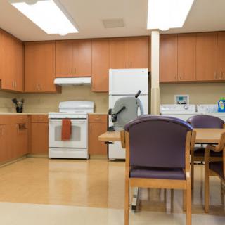 A modern kitchen and dining area featuring wooden cabinets, a stove, refrigerator, and a table with chairs.