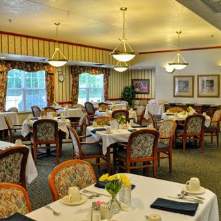 An elegant dining room with neatly arranged tables and chairs, featuring chandeliers and tasteful decor.