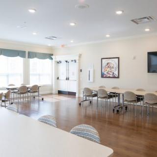 A bright, empty conference room with tables and chairs arranged neatly.