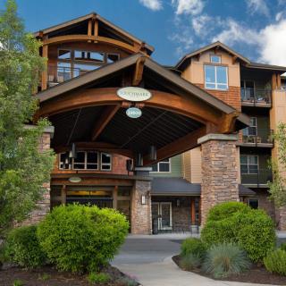 A beautiful hotel entrance featuring rustic architecture surrounded by lush greenery.