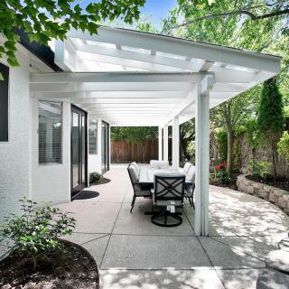 A modern patio with a pergola and outdoor dining set in a garden setting.