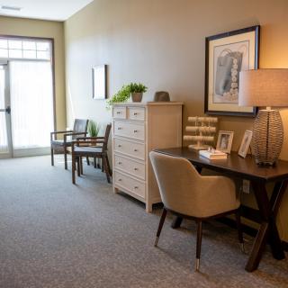 A well-furnished hallway with a desk, lamp, chairs, and decorative items.
