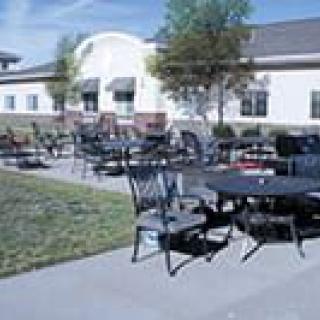 Outdoor patio area with tables and chairs in front of a building.