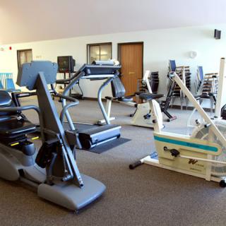 A fitness center with various exercise equipment including cardio machines and strength training gear.