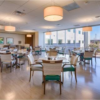 A spacious and well-lit dining area featuring modern furnishings and large windows, perfect for enjoying meals.