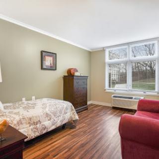 A cozy and inviting bedroom featuring a single bed, a stylish armchair, and large windows that invite natural light.