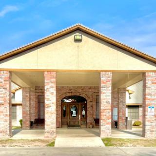 A welcoming entrance to a well-structured building featuring brick columns and a clear blue sky.