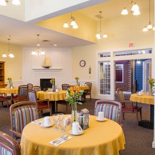 A bright and inviting dining area set for a meal, featuring yellow tablecloths and comfortable seating.